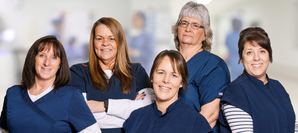 A group of female Caldwell Medical employees taking a group picture in their scrubs as they work in the hospital. 