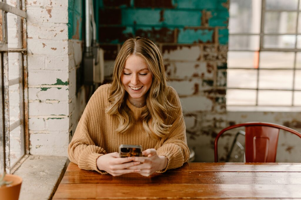 woman sitting in cafe looking at hospital app on her cell phone